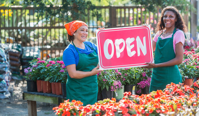 Two women holding business open sign