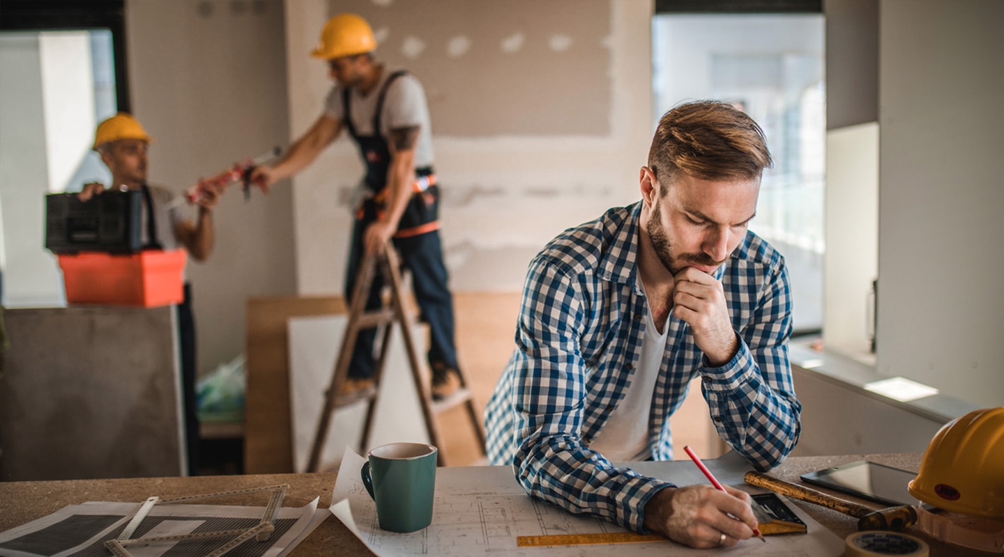 Man planning construction with workers in background