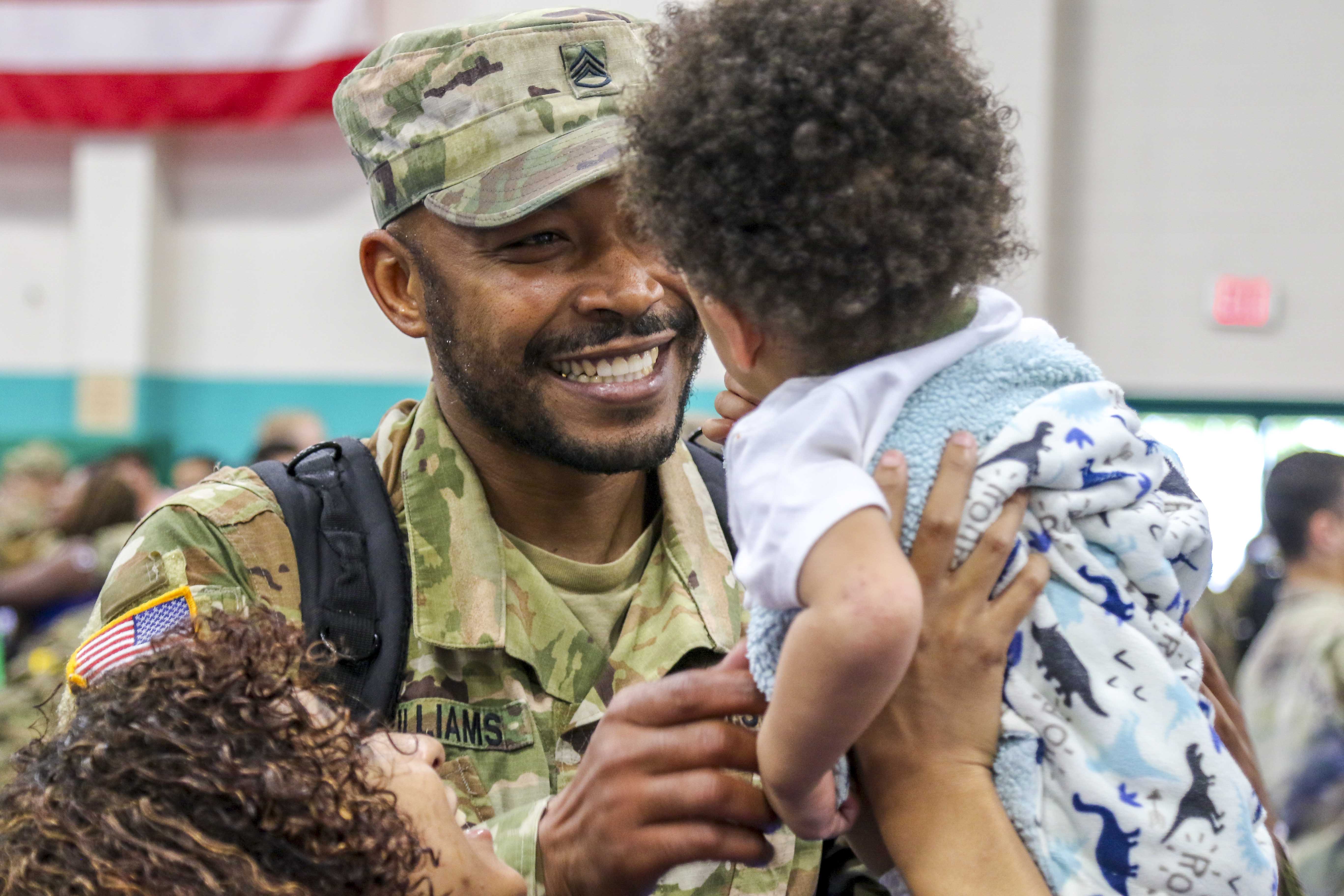 father in army uniform holds a young boy in his hands
