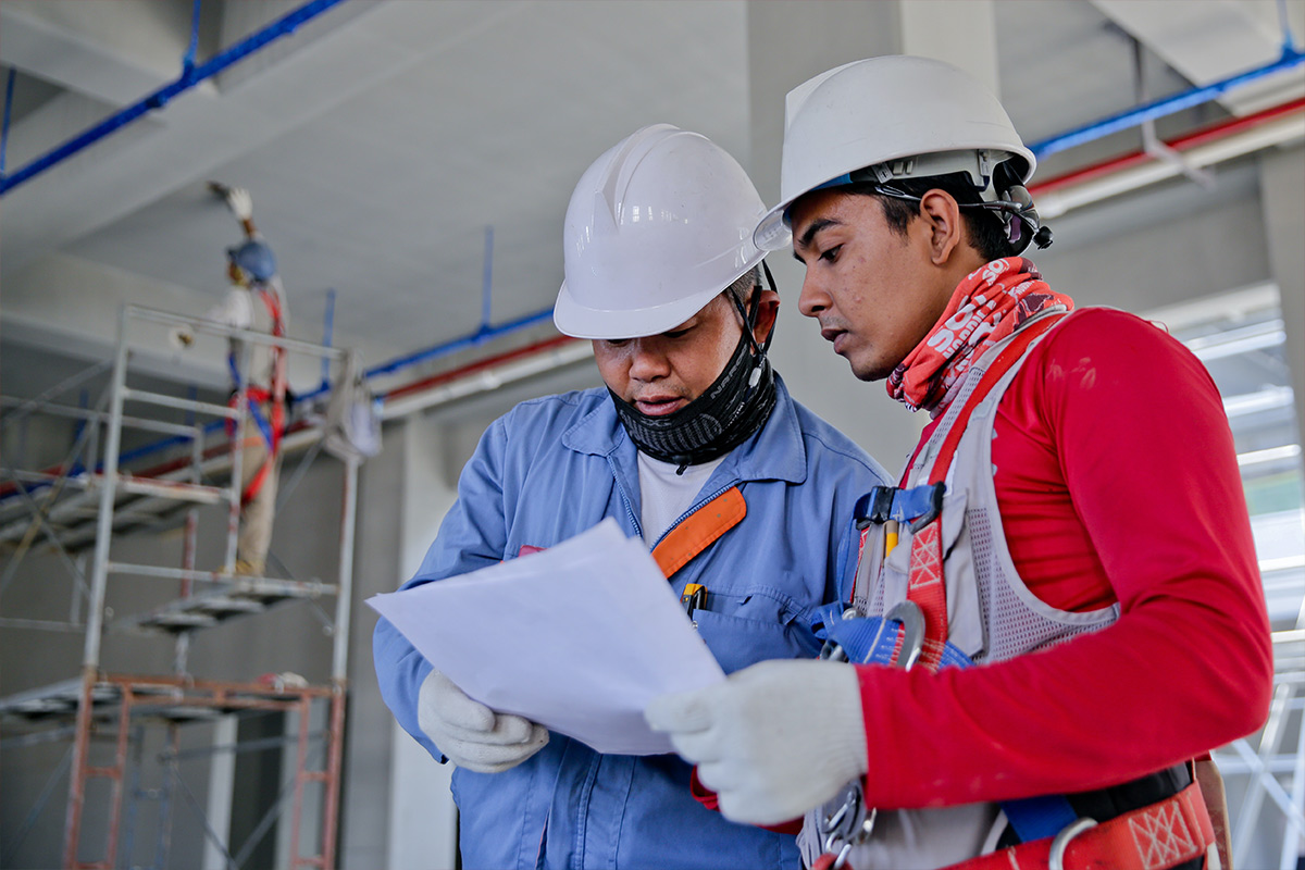 Two men in hardhats studying plans